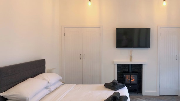 A bedroom with a bed, a television, a fireplace, and a wardrobe.