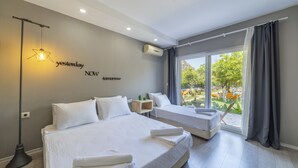 A modern hotel room with two beds, a large window with curtains, a star-shaped light fixture, and a wall-mounted air conditioner. - Gizli Koy Hotel (Kemer)