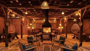 A rustic interior with a central wood-burning stove, stone flooring, and wooden furniture. - Gizli Koy Hotel (Kemer)