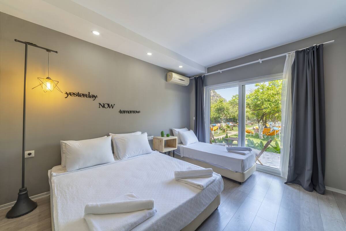 A modern hotel room with two beds, a large window, and a star-shaped light fixture.