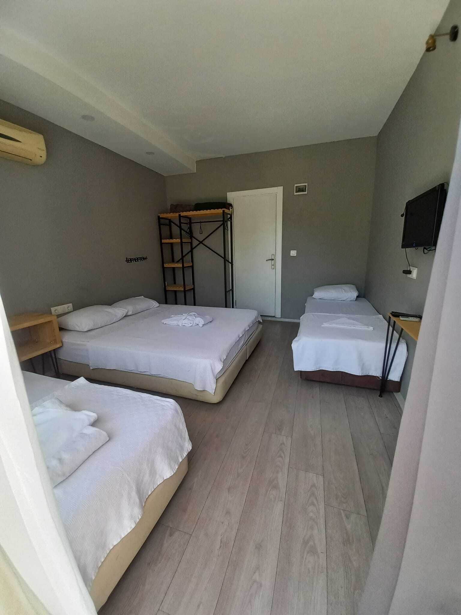 Una habitación con dos camas, una litera, una puerta, un televisor y un estante de madera.