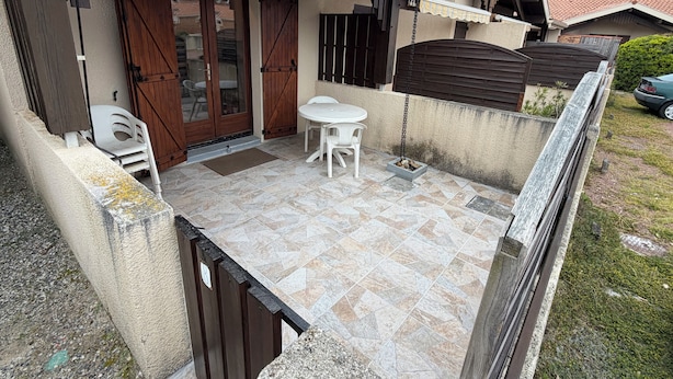 Eine kleine Terrasse mit Tisch und Stühlen, einem Holztor und einem Fliesenboden.