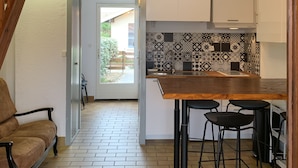 Eine Küche mit einem Holztisch, schwarzen Barhocker und fliesenbesetzter Spritzschutzwand.
