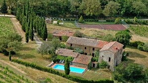 A stone villa with a swimming pool, surrounded by vineyards and a tennis court. - Traumblick in die Toskana - Appartment mit Pool auf Hügel zw. Siena u. Florenz (Toscana)