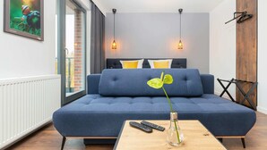 A modern living room with a blue sofa, a wooden coffee table, and a vase with a plant.