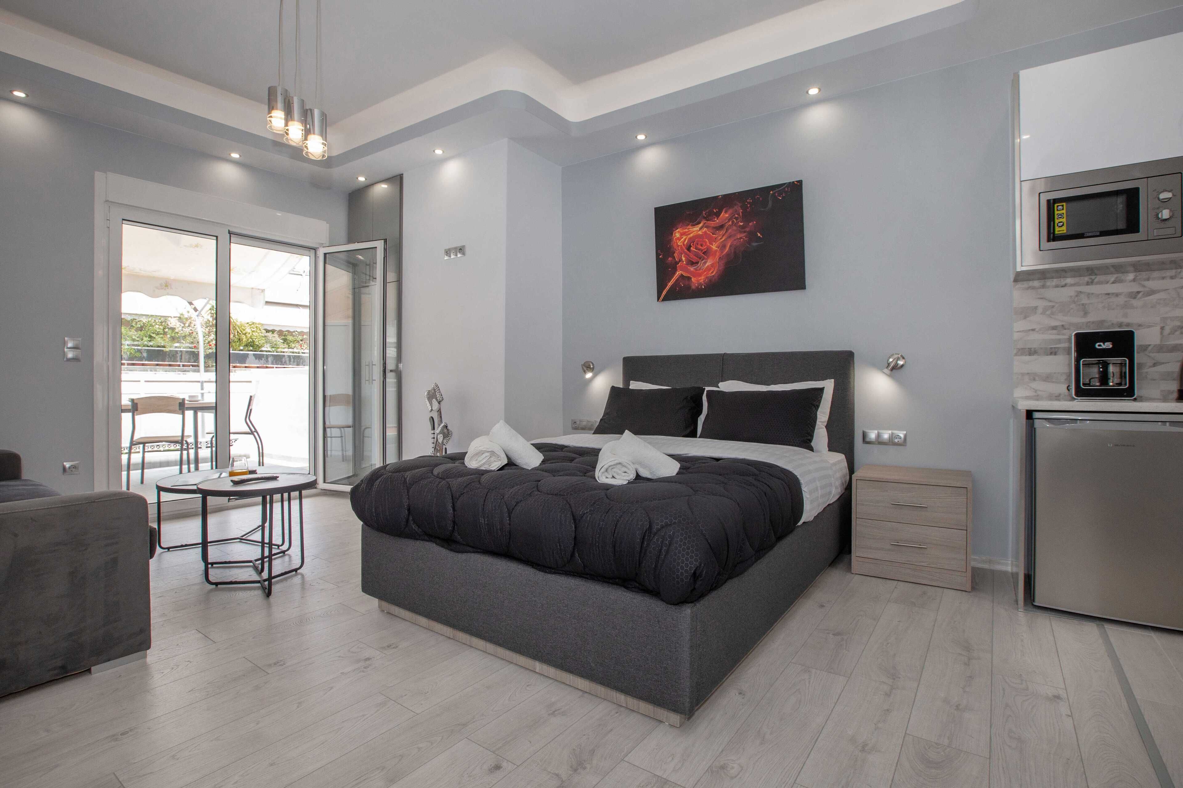 A modern bedroom with a large bed, a dining table, and a kitchenette.