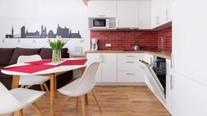 Una cocina moderna con armarios blancos, salpicadero de baldosas rojas y microondas.