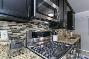 A kitchen with a stainless steel stove, a microwave, and a toaster.