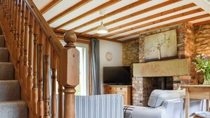 A cozy living room with a wooden staircase, a fireplace, a television, and a comfortable sofa. - 3 bedroom accommodation in Little Edstone, near Pickering (Little Edstone, near Pickering)