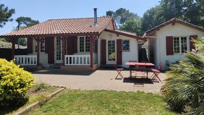 Una casa a due piani con tetto in tegole, un portico con ringhiera bianca e un patio con tavolo e sedie.