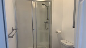 Une petite salle de bain moderne avec une douche à parois de verre, des toilettes et un porte-serviettes.