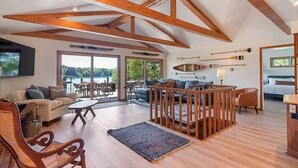 Un vaste espace de vie agrémenté de poutres en bois, une grande fenêtre offrant une vue panoramique, un canapé, une table basse et un coin repas.