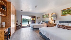 Une chambre d’hôtel avec deux lits, un bureau, une chaise, un fauteuil à bascule et une vue sur l’extérieur.