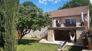 A stone house with a tiled roof, a balcony with outdoor furniture, and a hammock. - Bergerie du Mas de Darre (with spa, terrace and garden) between Lot and Aveyron. (Sainte-Croix)