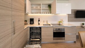 Een moderne keuken met houten kastjes, een vaatwasser, een oven en een ingebouwde televisie.