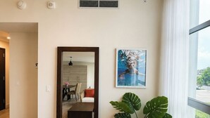 Een moderne woonkamer met een grote spiegel, een schilderij en een plant.