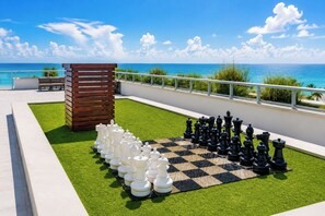 A chessboard set up on a rooftop terrace with a view of the ocean. - Hollywood Beach Steps Away - Amazing Apartment! (Hollywood)