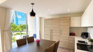Een moderne keuken met een eethoek, houten kastjes en uitzicht op het groen.
