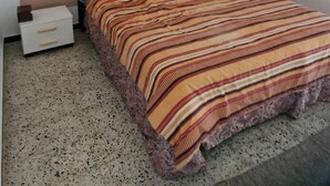 Een slaapkamer met een bed, nachtkastje en wand.