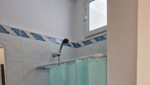 Een badkamer met douchegordijn, wastafel en raam.