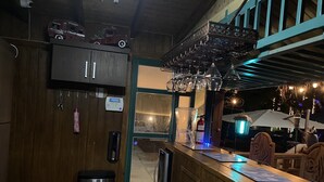 A bar area with wooden walls, a TV mounted above the bar, a trash bin, and a fire extinguisher. - Poblado Log Cabin Camper  (Boquerón)