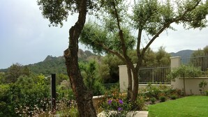 A garden with a stone bench, a tree, and a view of mountains. - Villa Luigi in Poggio dei Pini: villa accommodation with parking and wallbox (Capoterra)