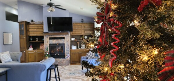A living room with a fireplace, a television, and a Christmas tree.