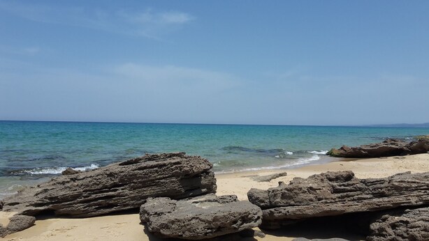 Una playa con agua turquesa cristalina y formaciones rocosas.