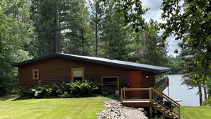 A cabin with a deck and a view of a lake. - Whispering Pines Lakeside Retreat  (Park Rapids)