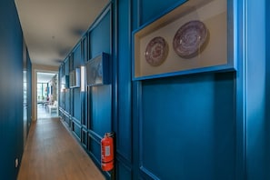 Un pasillo con paredes azules, obras de arte enmarcadas y un extintor.