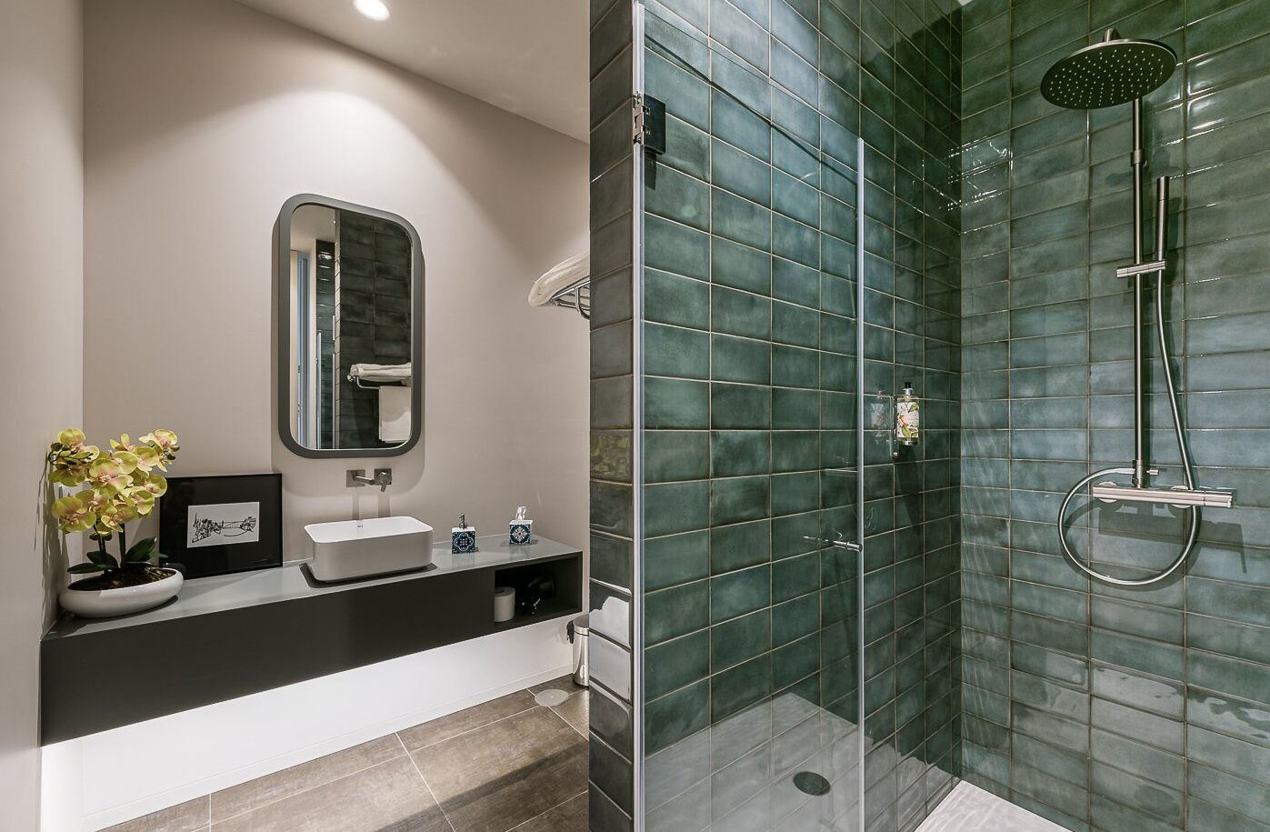 Un bagno dal design moderno, con un ampio specchio, un lavandino e una doccia con cabina in vetro.