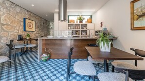 A modern kitchen with a stone wall, a central island, and a dining area with chairs and a table.