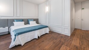 Une chambre à coucher moderne avec un grand lit, des murs blancs et un plancher en bois.