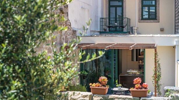 A two-story building with a balcony, outdoor seating area, and potted plants.