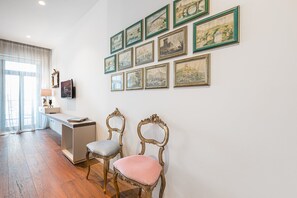 A room with a desk, two chairs, and a wall adorned with framed pictures.