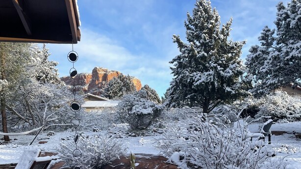 A snow-covered garden with a hammock and a bench, a rock formation in the background, and a clear sky. - Peaceful Sedona retreat with red rock views, walk to Sedona Golf Resort (Sedona)