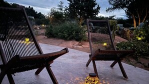 Two wooden lounge chairs with metal frames, a decorative lantern, and a paved outdoor area with plants and trees. - Peaceful Sedona retreat with red rock views, walk to Sedona Golf Resort (Sedona)