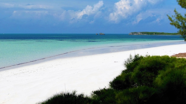 A beach with clear turquoise water, white sand, and a distant rocky outcrop. - Private Waterfront  Home With 180* Sea Views - 2 Bed / 2Bath (Spanish Wells)