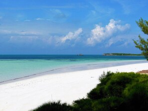 A beach with clear turquoise water, white sand, and a distant rocky outcrop. - Private Waterfront  Home With 180* Sea Views - 2 Bed / 2Bath (Spanish Wells)