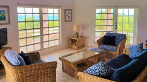 A room with wicker furniture, large windows, a ceiling fan, and a view of the ocean. - Private Waterfront  Home With 180* Sea Views - 2 Bed / 2Bath (Spanish Wells)