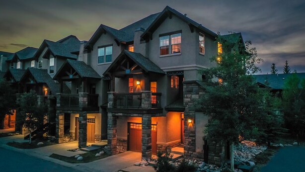 A multi-story house with a stone facade, multiple balconies, and a well-lit entrance. - Luxury Downtown Condo - Private Hot Tub! Walk to Dining and Ski Bus... (Winter Park)