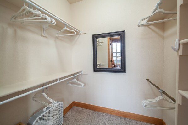A small, well-lit walk-in closet with white hangers and shelves, a mirror, and a wooden floor. - Luxury Downtown Condo - Private Hot Tub! Walk to Dining and Ski Bus... (Winter Park)