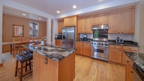 A spacious kitchen with wooden cabinets, stainless steel appliances, and a granite countertop. - Luxury Downtown Condo - Private Hot Tub! Walk to Dining and Ski Bus... (Winter Park)