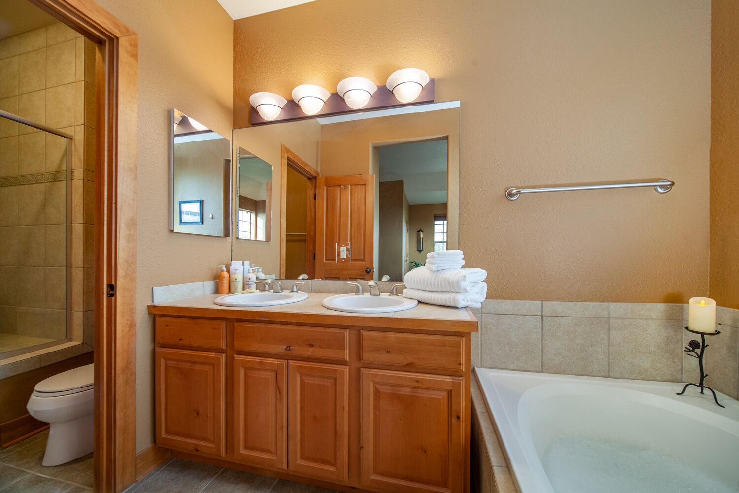 Une salle de bain avec un meuble-lavabo en bois, deux vasques, un grand miroir et une baignoire.