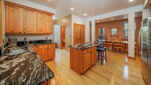 A spacious kitchen with wooden cabinets, granite countertops, and a central island. - Luxury Downtown Condo - Private Hot Tub! Walk to Dining and Ski Bus... (Winter Park)