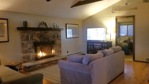 A living room with a fireplace, a sofa, and a television. - Pocono Cabin in Masthope Mountain Community (Lackawaxen)