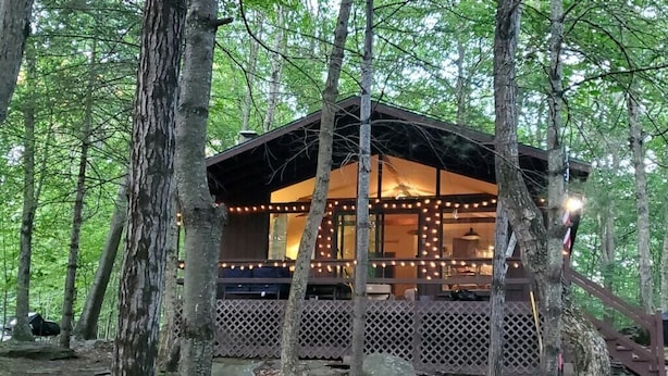 A cabin with a wooden deck, surrounded by trees. - Pocono Cabin in Masthope Mountain Community (Lackawaxen)