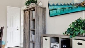 A room with a wooden cabinet, a television displaying a beach scene, and a door.