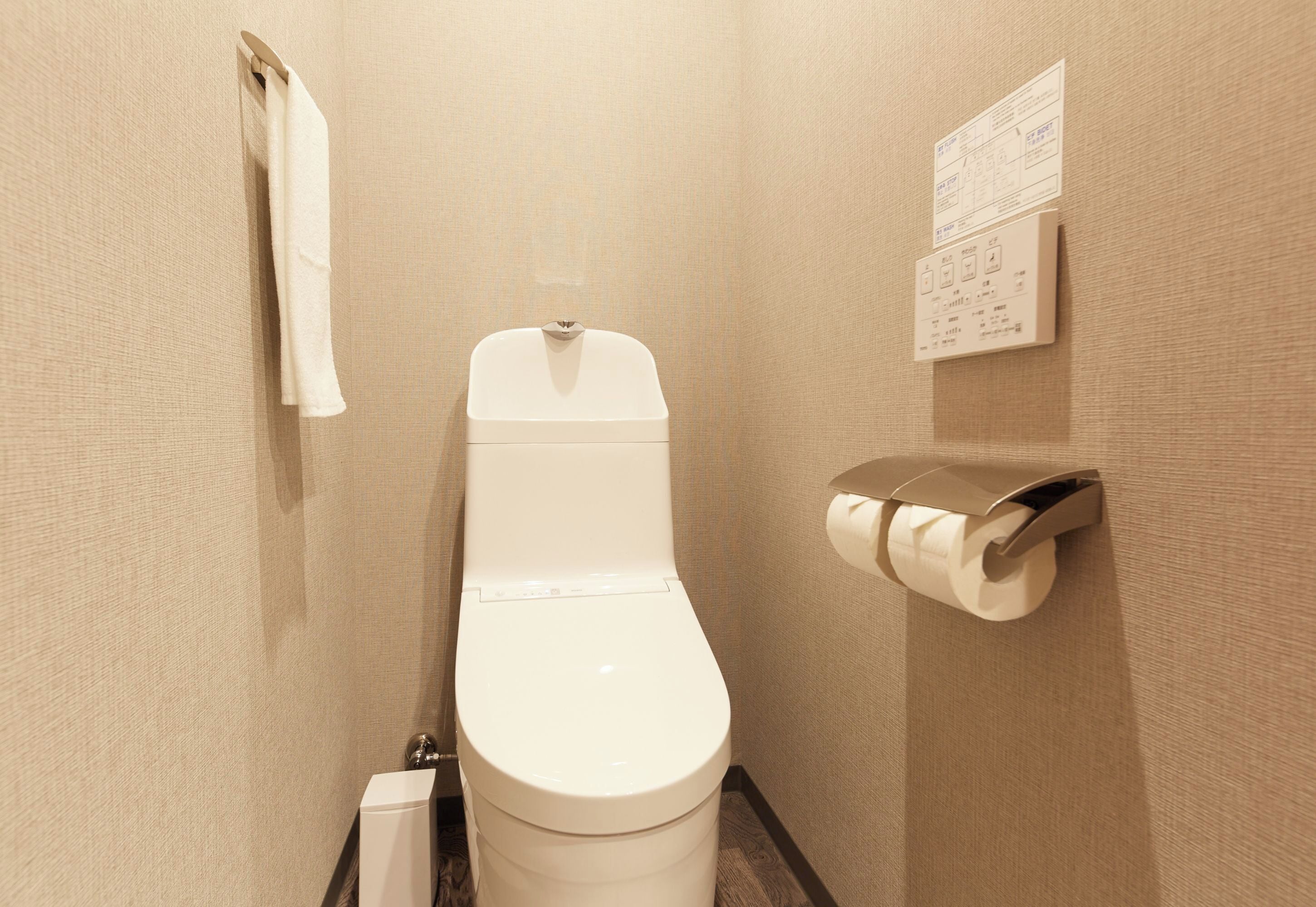 A small, modern bathroom with a toilet, a towel rack, and a toilet paper holder.
