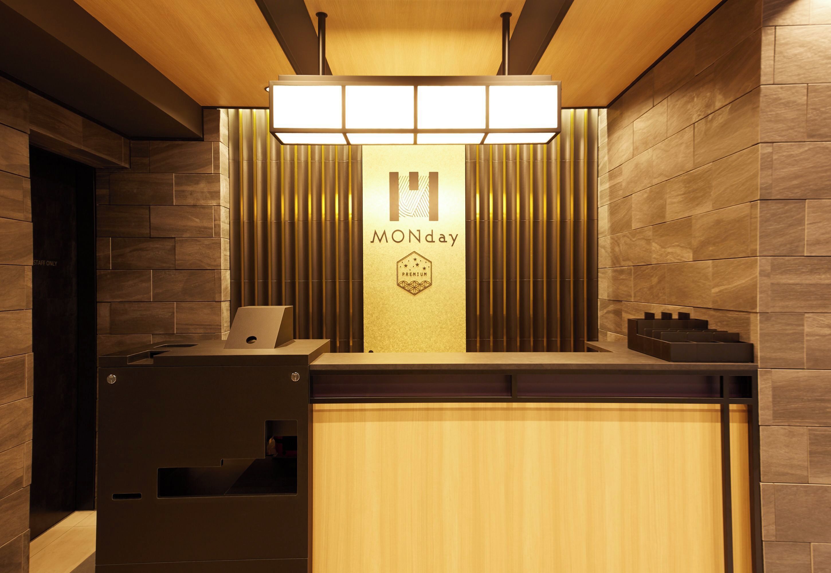 A reception desk with a wooden finish, a 'MONday' sign, and a modern light fixture above.